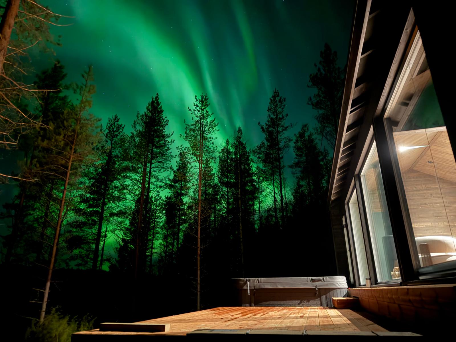 Northern lights over the forest beside the villa deck