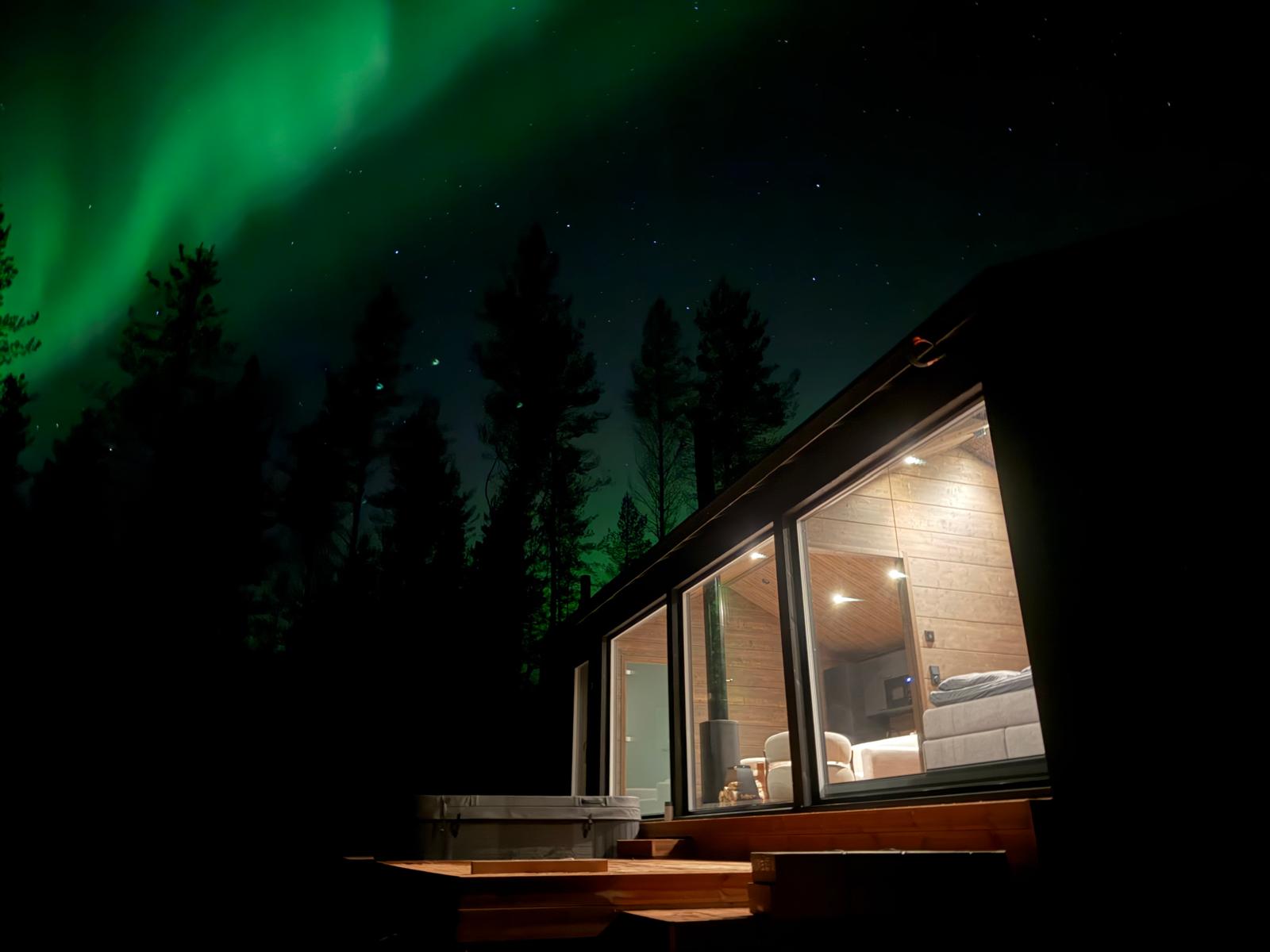 Northern lights over a villa with its windows lit